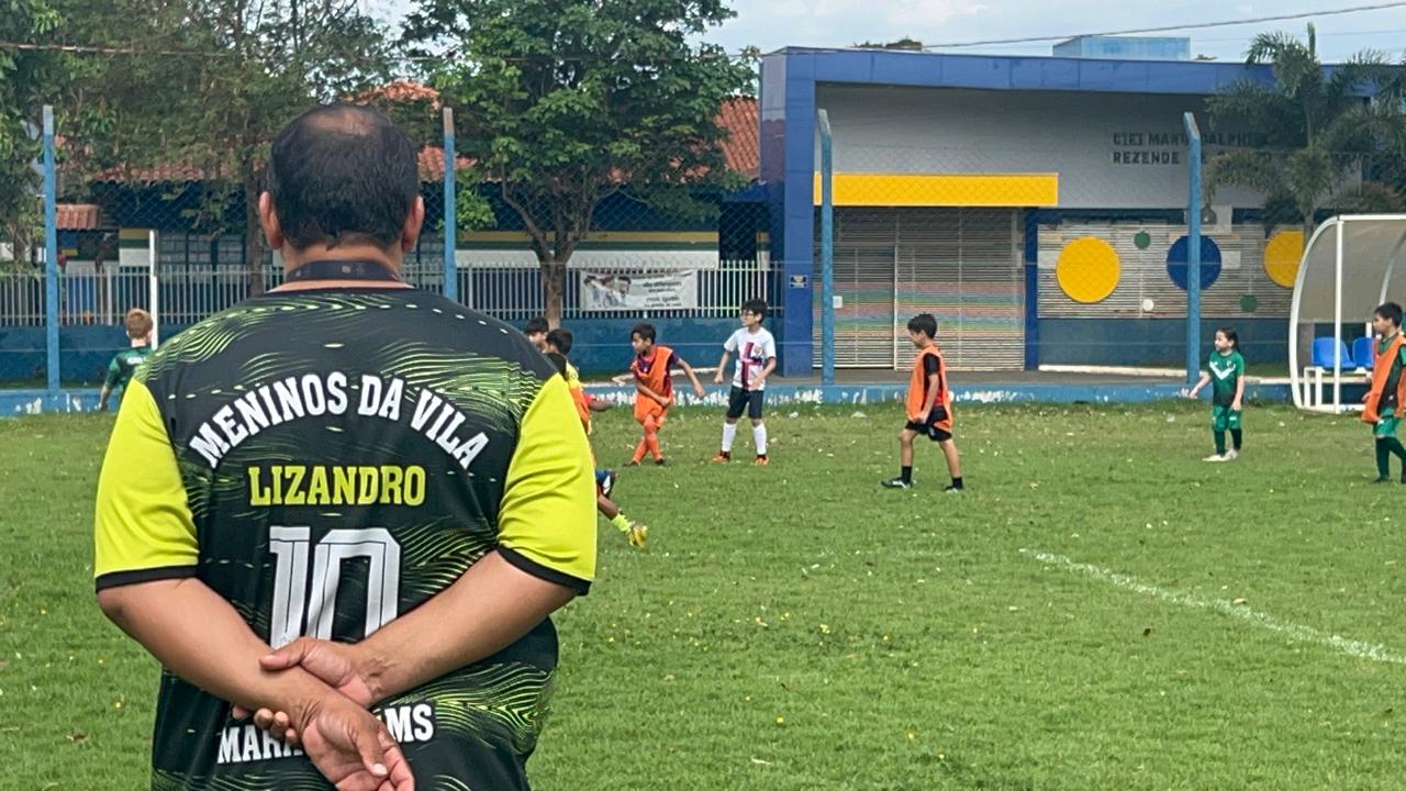 Professor acompanha as crianças jogando futebol no Dia das Crianças MDV